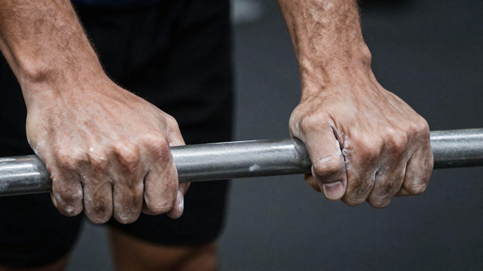 Chalked hands gripping a knurled bar